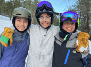 Three young students smiling in snow gear